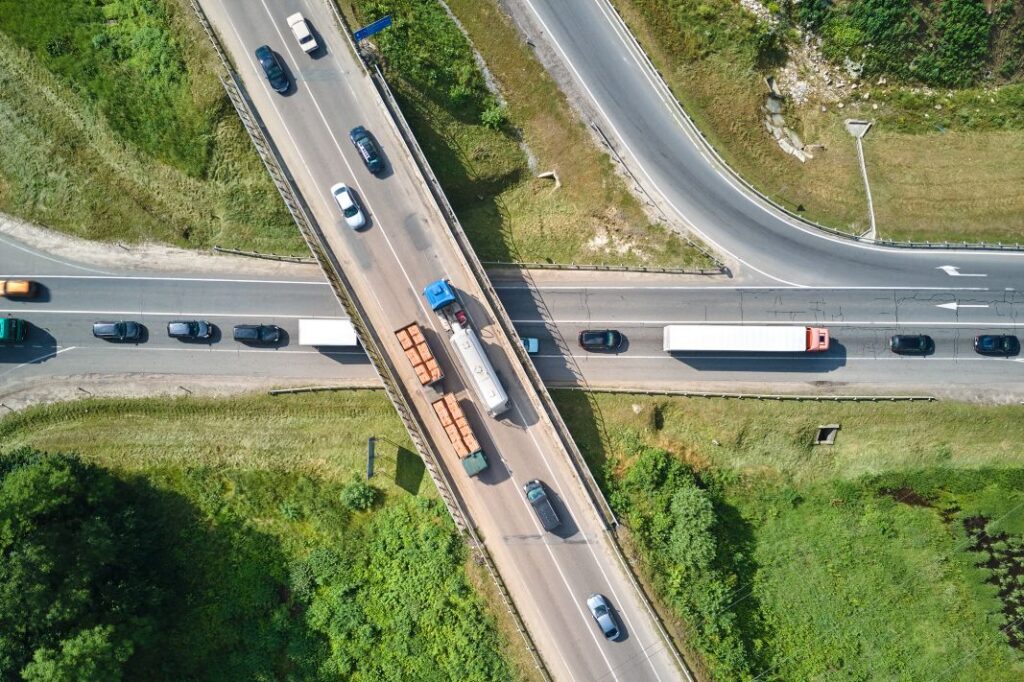 Transportation supports urban growth: aerial view of a busy city intersection with fast-moving cars and trucks during rush hour.