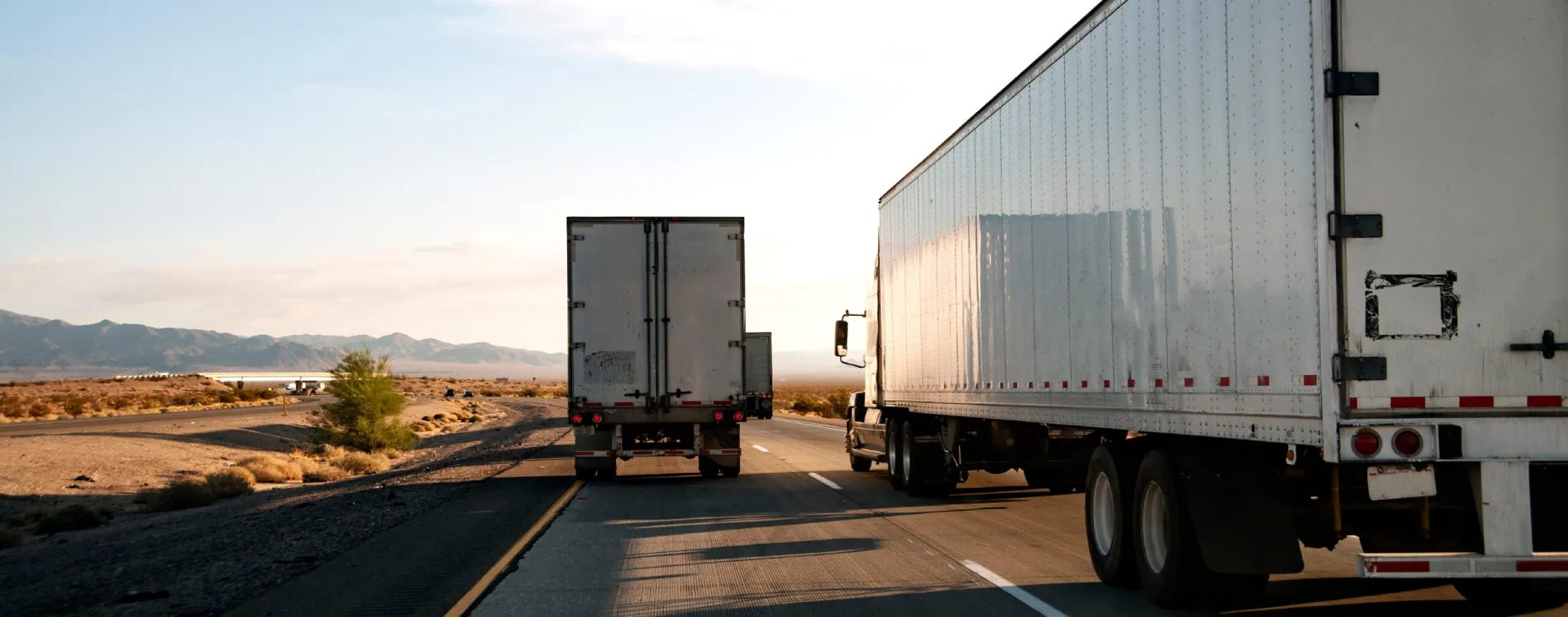 Two semi-trucks hauling freight on a desert highway in Arizona, representing Cosic LLC's Arizona freight brokerage carrier network moving loads across the Southwest.