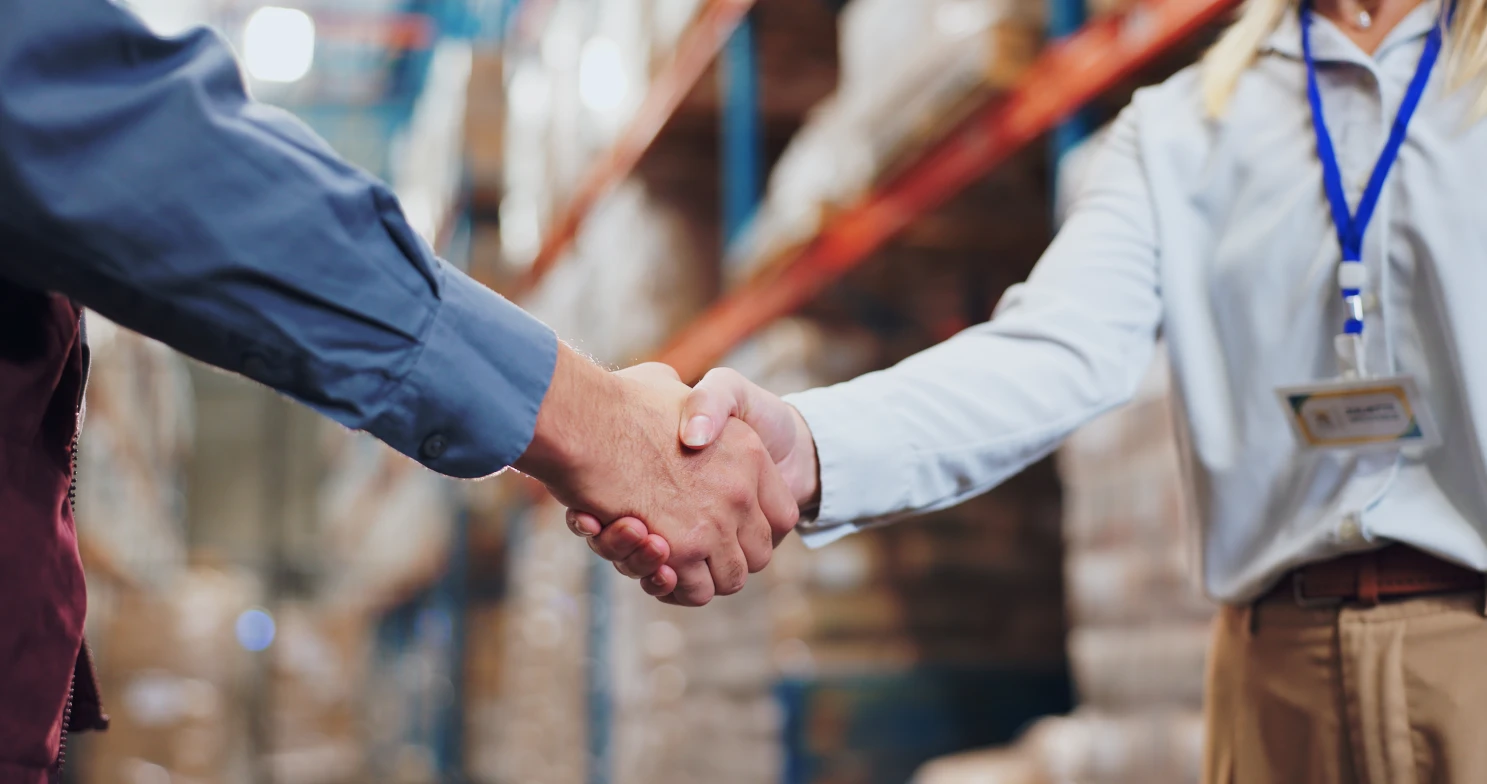 Warehouse manager and supplier shaking hands, supply chain solutions for industrial suppliers built on trusted partnerships
